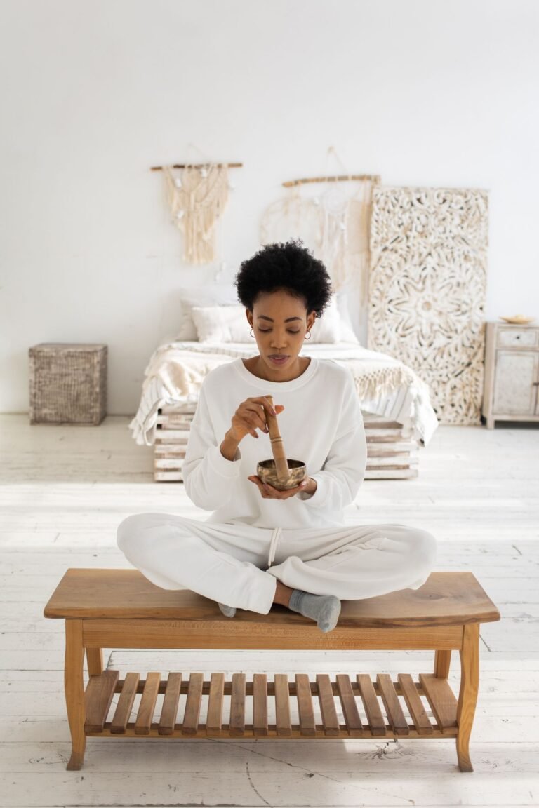 African American woman using a Tibetan singing bowl for sound therapy in a serene indoor setting.